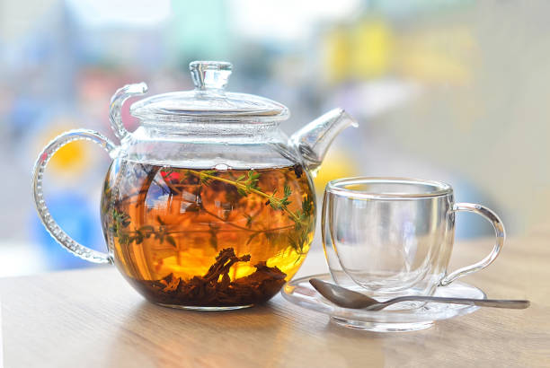 istock GLASS KETTLE WITH TEA AND EMPTY GLASS CUP ON A LIGHT BACKGROUND 1200277020