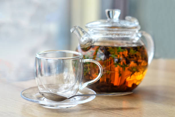 istock GLASS KETTLE WITH TEA AND EMPTY GLASS CUP ON A LIGHT BACKGROUND 1200277027