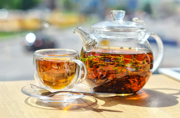 istock A  glass teapot with tea and a glass cup with tea stand on the table ON A LIGHT BACKGROUND 1200277206