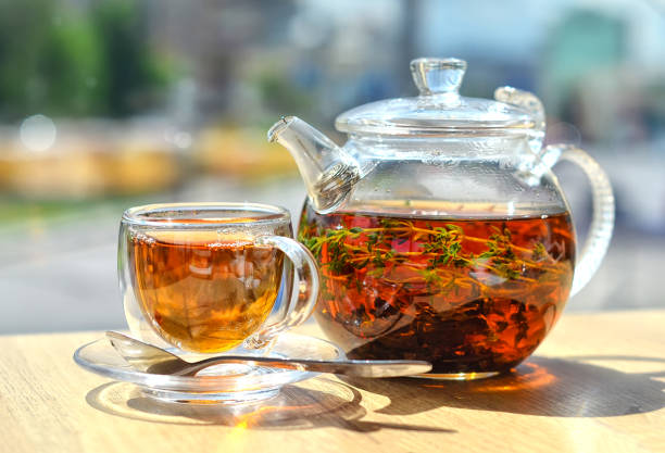 istock A  glass teapot with tea and a glass cup with tea stand on the table ON A LIGHT BACKGROUND 1200277245