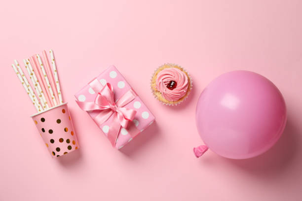 istock Gift box, balloon, cupcake and paper cup with straws on pink background, top view 1200278491