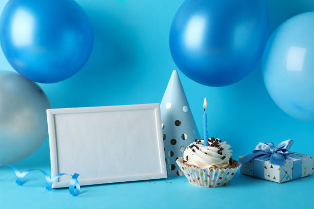 istock Balloons, birthday hat, cupcake, frame and gift box on blue background, space for text 1200278567