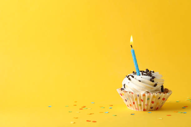 istock Cupcake with candle on yellow background, space for text 1200279152