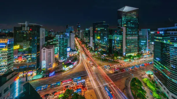 Panorama aerial view of famous crowded Crossing at Downtown Gangnam Station at Night with motion blured traffic lights and surrounding modern skyscrapers. Gangnam District, Seoul, South Korea, Asia.