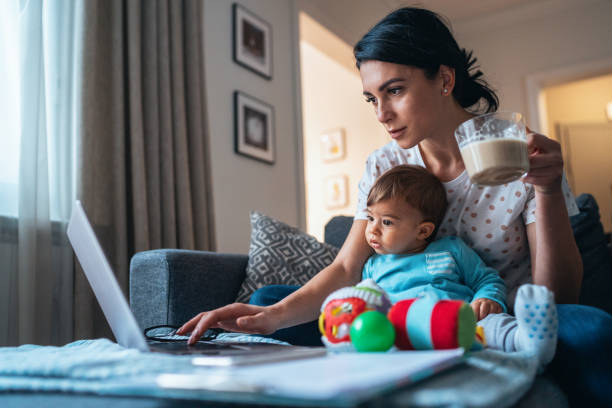 Working at home mom Young modern mother with a baby using laptop at home multi tasking stock pictures, royalty-free photos & images