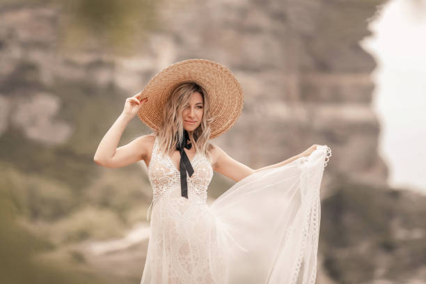 Young beautiful pregnant woman dressed in a long white dress and lace hat outdors Young beautiful pregnant woman dressed in a long white dress and lace hat outdors. beach wedding Straw Hat stock pictures, royalty-free photos & images