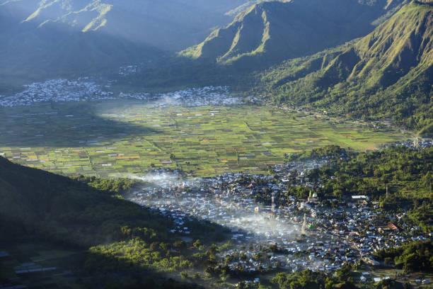 View from above, stunning aerial view of the Sembalun village with the agricultural fields illuminated at sunrise. Sembalun is situated on the slope of mount Rinjani and is surrounded by beautiful green mountains. Sembalun, Lombok, West Nusa Tenggara, Indonesia. vista desde arriba, impresionante vista aérea de la aldea de sembalun con los campos agrícolas iluminados al amanecer. el sembalun está situado en la ladera del monte rinjani y está rodeado de hermosas montañas verdes. sembalun, lombok, nusa tenggara