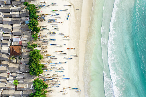 Vista desde arriba, impresionante vista aérea de un pueblo de pescadores con casas y barcos en una playa de arena blanca bañada por un hermoso mar turquesa. Playa Tanjung Aan, al este de Kuta Lombok, Oeste Nusa Tenggara, Indonesia. photo