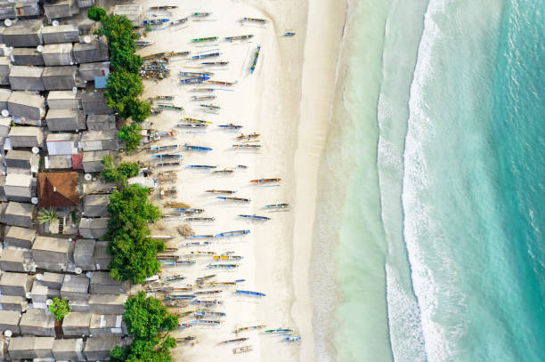 vista dall'alto, splendida vista aerea di un villaggio di pescatori con case e barche su una spiaggia di sabbia bianca bagnata da un bellissimo mare turchese. tanjung aan beach, a est di kuta lombok, west nusa tenggara, indonesia. - tenggara foto e immagini stock