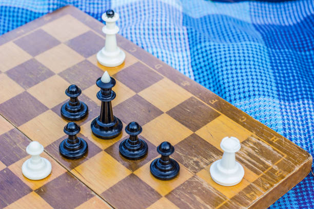 istock creative foreshortening from above chess concept with wooden desk with black and white figures on game space and lay near on carpet background texture, copy space for your text 1200297874