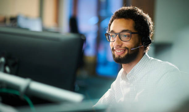 happy male call handler a male call center worker takes a call. headset photos stock pictures, royalty-free photos & images