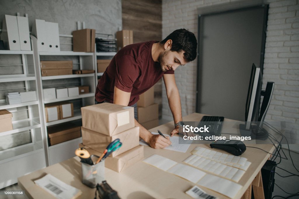 Bar codes helping me to organize packages Delivery person preparing bar codes for packages, checking to do list E-commerce Stock Photo