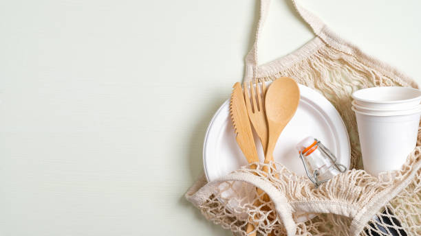 istock Eco friendly mesh grocery bag with zero waste reusable travel bamboo cutlery set, biodegradable paper plate and cups, glass bottle. Eco store banner template with copy space 1200302991
