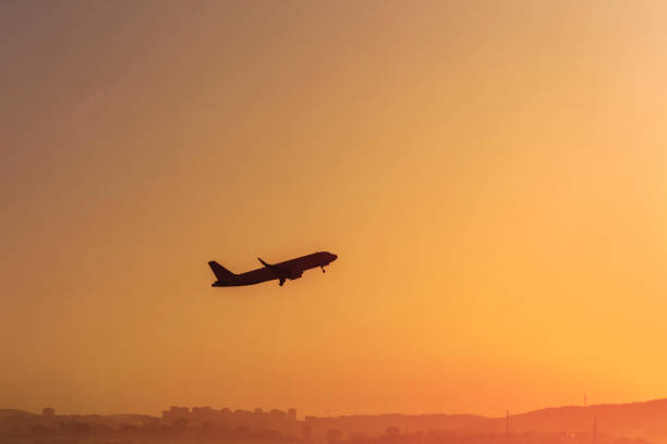istock Dark silhouette of a plane in orange sky. 1200304077