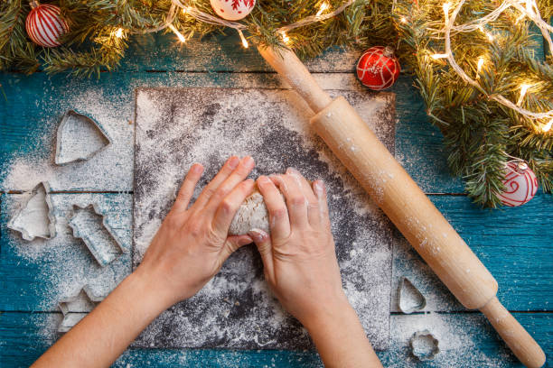 istock Photo of human hands, rolling pin, dough, spruce branches, garlands 1200305067