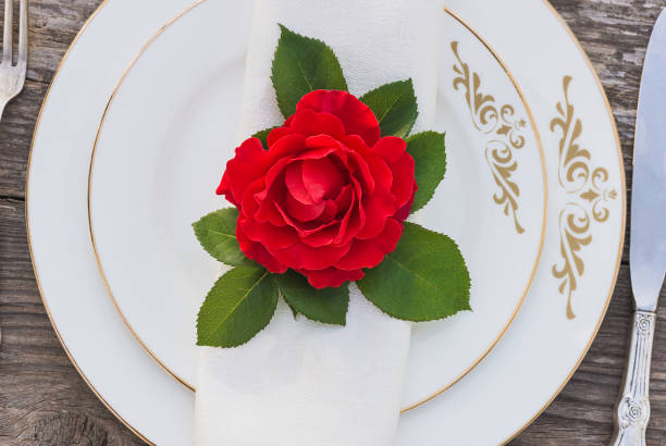 istock Festive table setting with red rose flower. Red rose flower on white linen napkin on white plates and vintage cutlery 1200307782