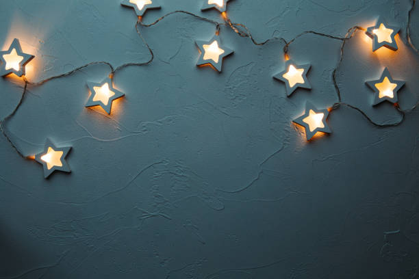 istock Burning Christmas garland on empty blue table 1200312624