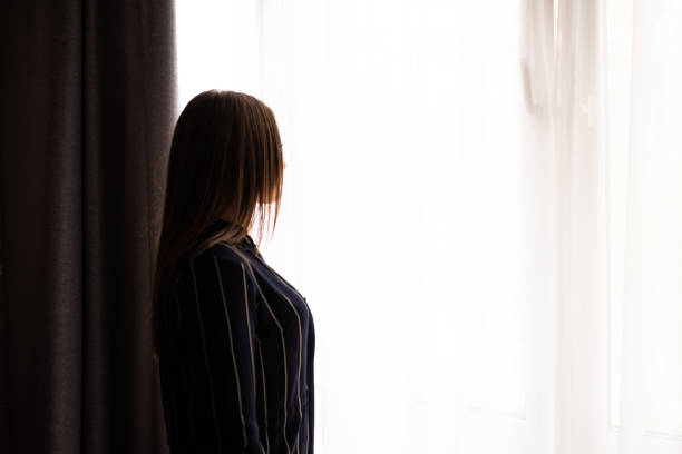 istock Brunette Woman Standing at Window 1200313029
