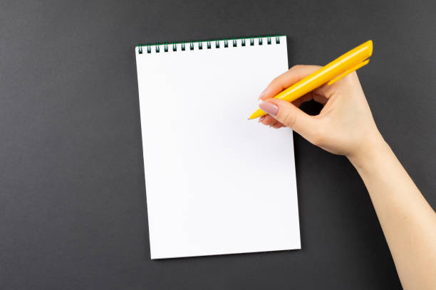 istock hands hold opened notebook pages with yellow pen 1200313107