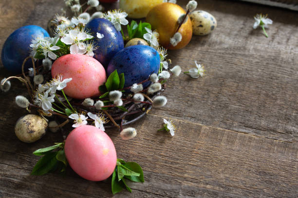 istock Colored Easter eggs in a nest with willow branches and spring flowers on a gray wooden background. Copy space. 1200315841