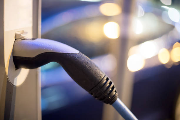 istock Charching an electric car with power cable supply, plugged in. Night. 1200317489