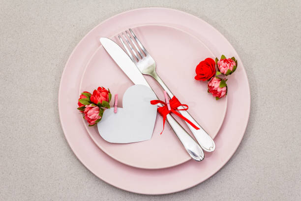 istock Romantic table setting on light stone concrete background. Valentine's day or Wedding card template. Paper heart, flowers, cutlery 1200318386