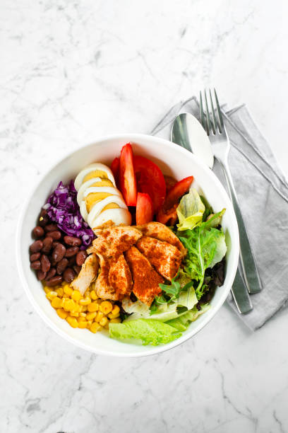 istock Top view of lunch bowl with chicken, egg, tomatoes, lettuce, corn, red beans, red cabbage. Clean food and dieting nutrition concept. Copy space, flat lay 1200318438