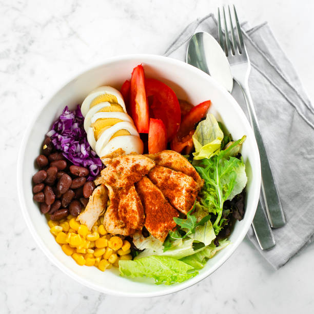 Top view of lunch bowl with chicken, egg, tomatoes, lettuce, corn, red beans, red cabbage. Clean food and dieting nutrition concept. Copy space, flat lay