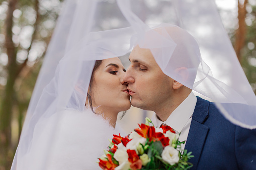 Happy bride and groom under a veil