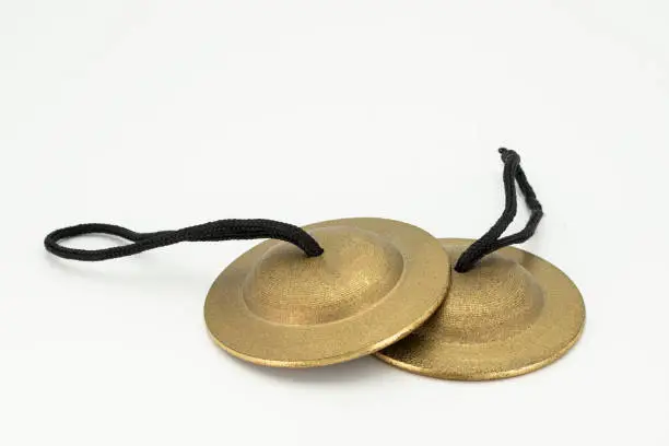 Closeup of a pair of finger cymbals lying on a white underground