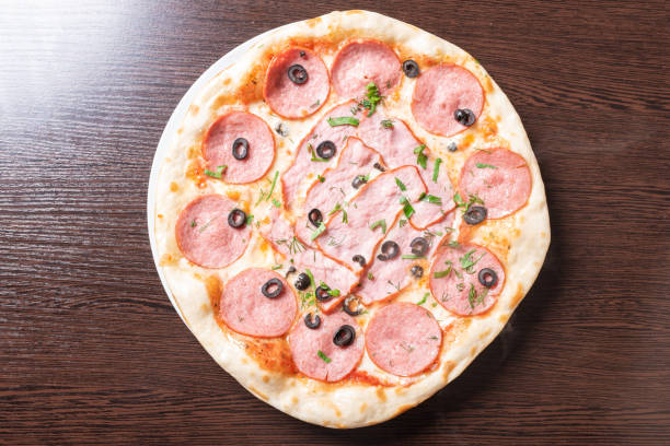 istock Cheap pizza with pepperoni, ham, olives and herbs. 1200321346
