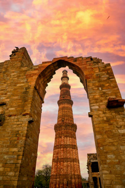 arche encadrant le célèbre point de repère le minar de qutub dans le delhi réglé sur le fond d'un ciel nuageux - delhi quitab minar qutab new delhi photos et images de collection