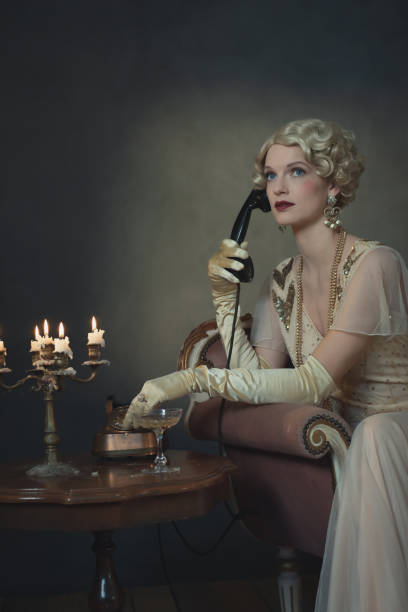 retro 1920 kobieta mody przez telefon siedząc na kanapie obok stołu ze świecznikiem i kieliszkiem szampana. - 1920s style image created 1920s 20s women zdjęcia i obrazy z banku zdjęć