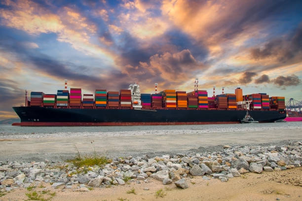 logistik und containerverladung durch große lastkähne auf dem seeweg in einem hafen voller container, die darauf warten, transportiert zu werden - tugboat towing nautical vessel industrial ship stock-fotos und bilder