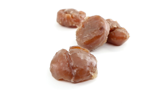 Marron glaces on white background. They are a confections made of chestnut candied in sugar syrup and glazed