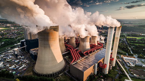 Aerial view of building exterior of a coal fired power station. Large cooling towers emitting steam into to air. Great for global warming, climate change and pollution themes.