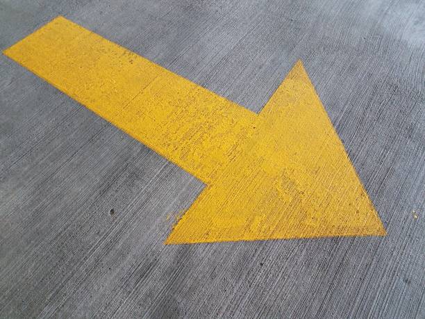 istock yellow arrow painted on grey cement on ground 1200334314