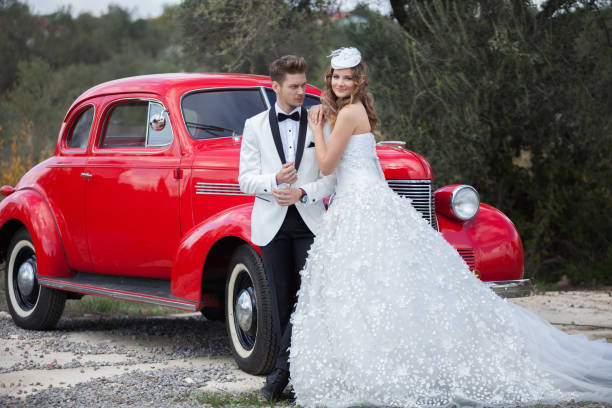 glückliche braut und bräutigam in der nähe des retro-auto - haute couture beautiful smoking beauty stock-fotos und bilder