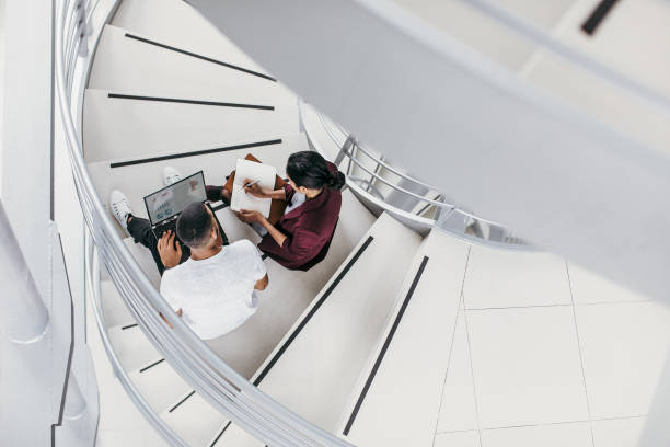 istock Business people sitting on the staircase, discussing 1200337411