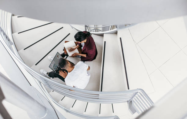 istock Business people sitting on the staircase, discussing 1200337425