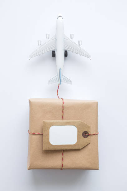 istock Cardboard delivery box with copy space label and small airplane abstract on white. 1200338016