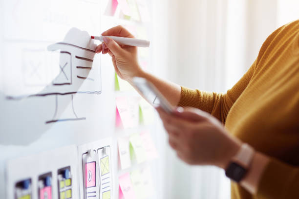 istock Woman planning website ux app development with marker pen on whiteboard 1200338019