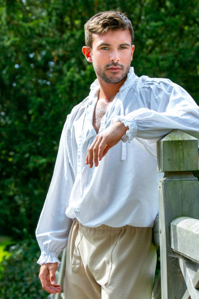 Portrait of handsome gentleman dressed in vintage costume standing on bridge of stately home with trees in background Portrait of handsome gentleman dressed in vintage costume standing leaning on post with trees in background regency style stock pictures, royalty-free photos & images