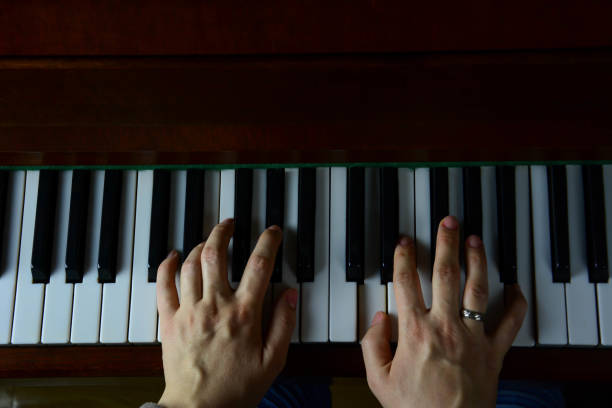 istock Woman hands playing the piano in top view 1200341958