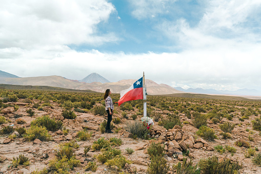 Young Caucasian woman standing near Chilean flag  in Atacama desert in Chile