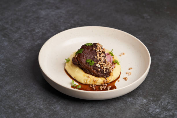 istock Stewed veal cheeks with mashed potatoes on a white plate, close-up. 1200344660