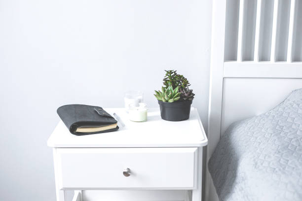 istock Tiny succulents, candles and black notebook on bedside table in the bedroom in scandinavian style home. Scandinavian interior in gray and white colors 1200344789