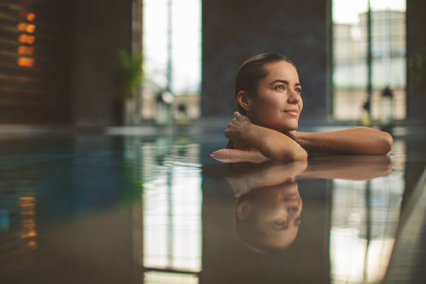 istock Beautiful young woman relaxing on indoors poolside 1200349245