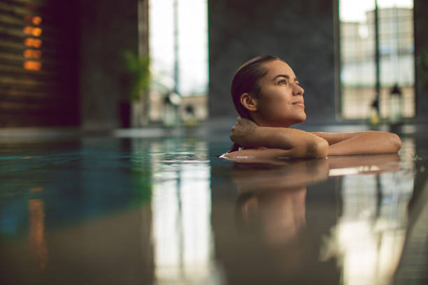 bella giovane donna rilassante al chiuso a bordo piscina - health spa immagine foto e immagini stock