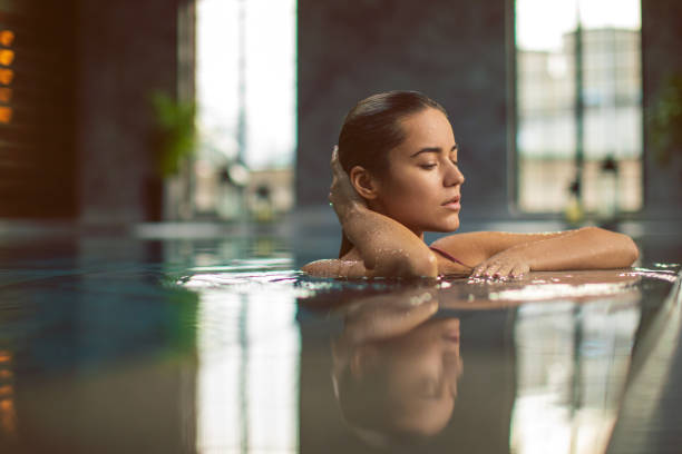 istock Beautiful young woman relaxing on indoors poolside 1200349325